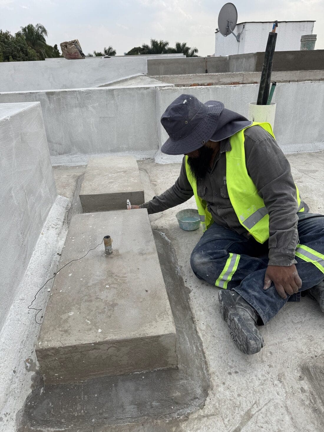Trabajador con chaleco reflejante sellando el pretil y el registro de una cubierta